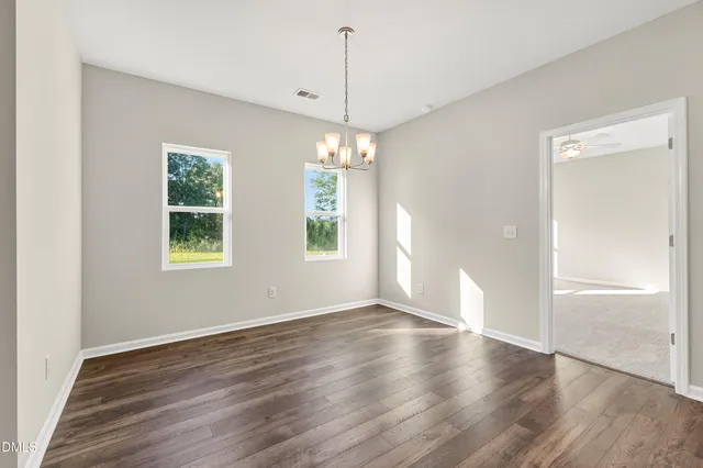 a view of a room with wooden floor chandelier and windows