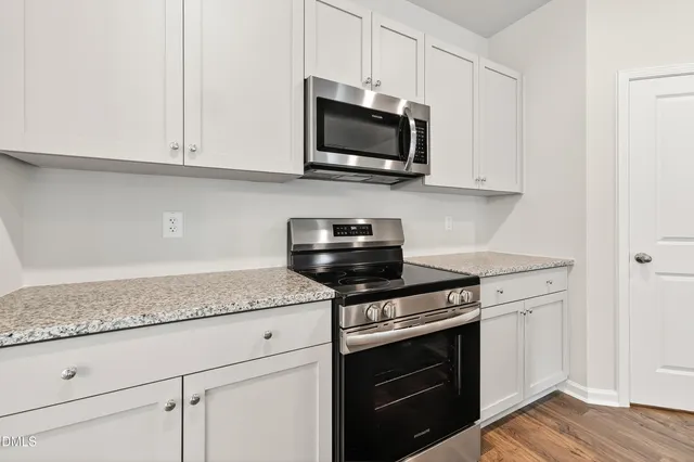 a kitchen with stainless steel appliances granite countertop white cabinets granite counter tops and a wooden floors