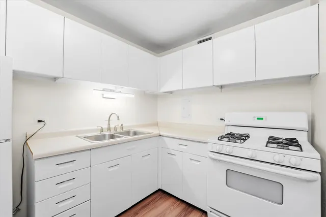 a kitchen with granite countertop white cabinets stove and sink