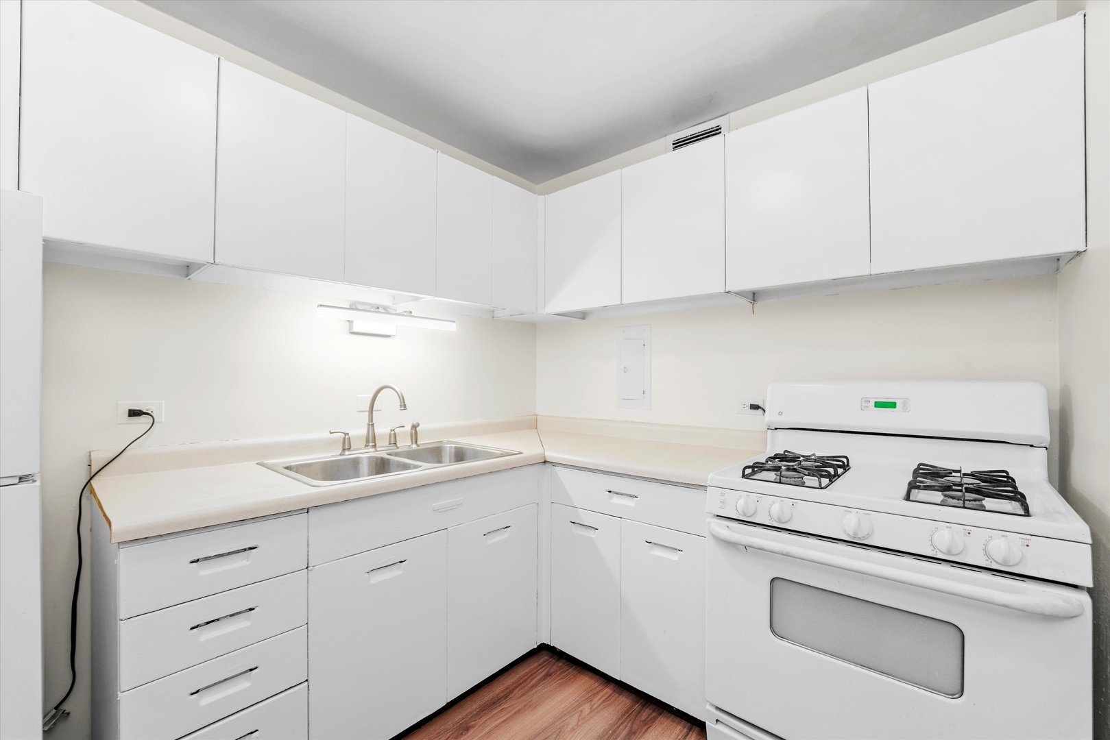 1450 East 55th Place, Unit 317S Chicago, IL 60637 - Photo 7 of 25 a kitchen with granite countertop white cabinets stove and sink