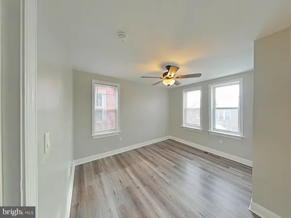 a view of empty room with wooden floor and fan
