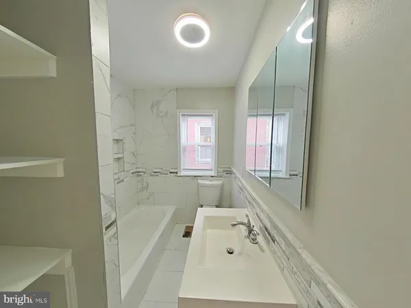 a bathroom with a tub sink and mirror