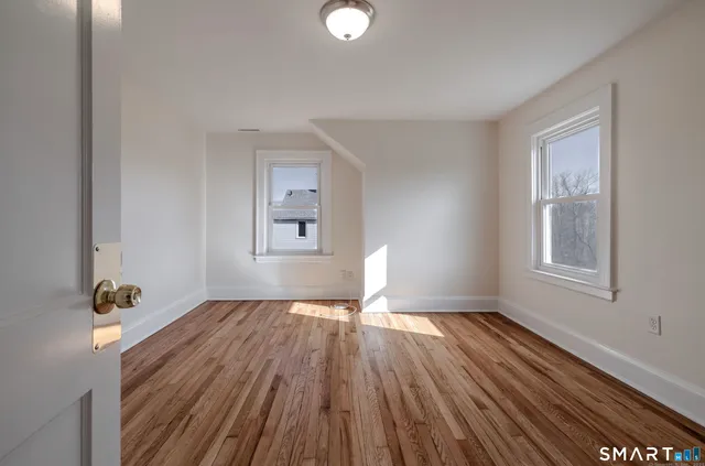 a view of an empty room with wooden floor and a window