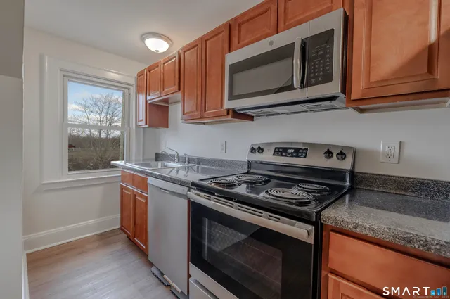 a kitchen with stainless steel appliances granite countertop white cabinets granite counter tops and a window