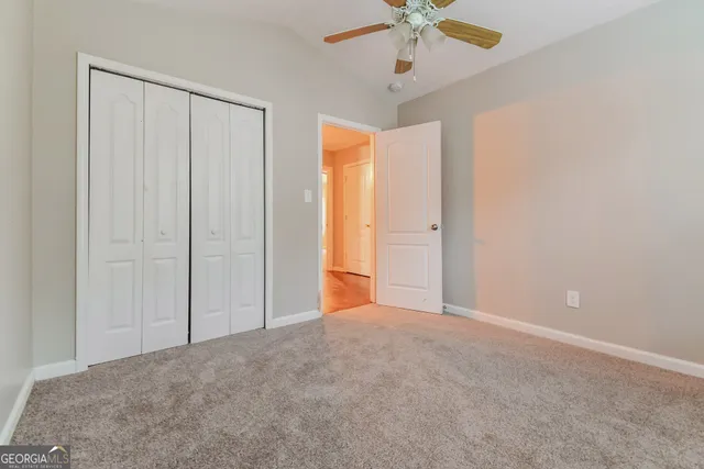 an empty room with closet and a chandelier fan