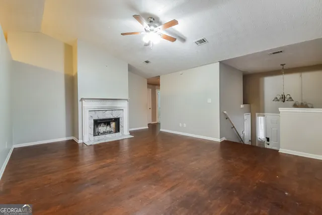 a view of a livingroom with a fireplace a ceiling fan and wooden floor