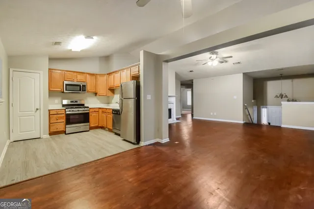 a view of kitchen with kitchen island a sink wooden floor and stainless steel appliances