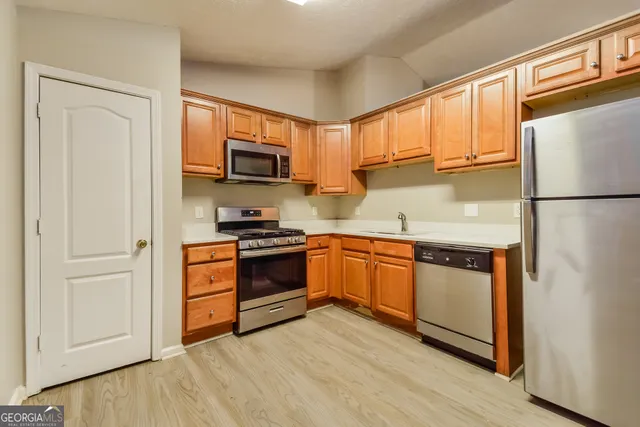 a kitchen with granite countertop a refrigerator stove top oven and sink