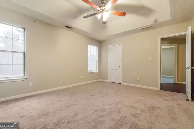 an empty room with windows and fan