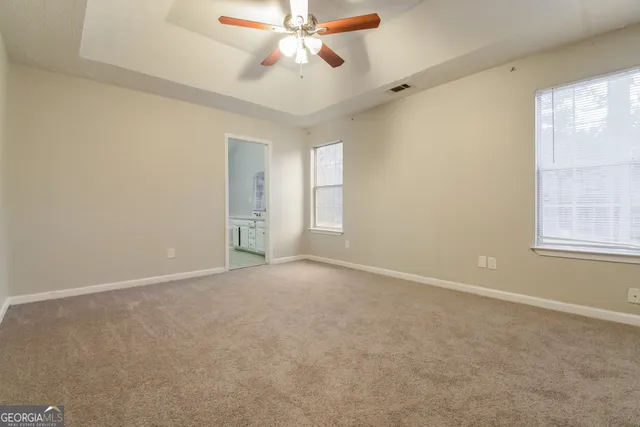 an empty room with windows and fan
