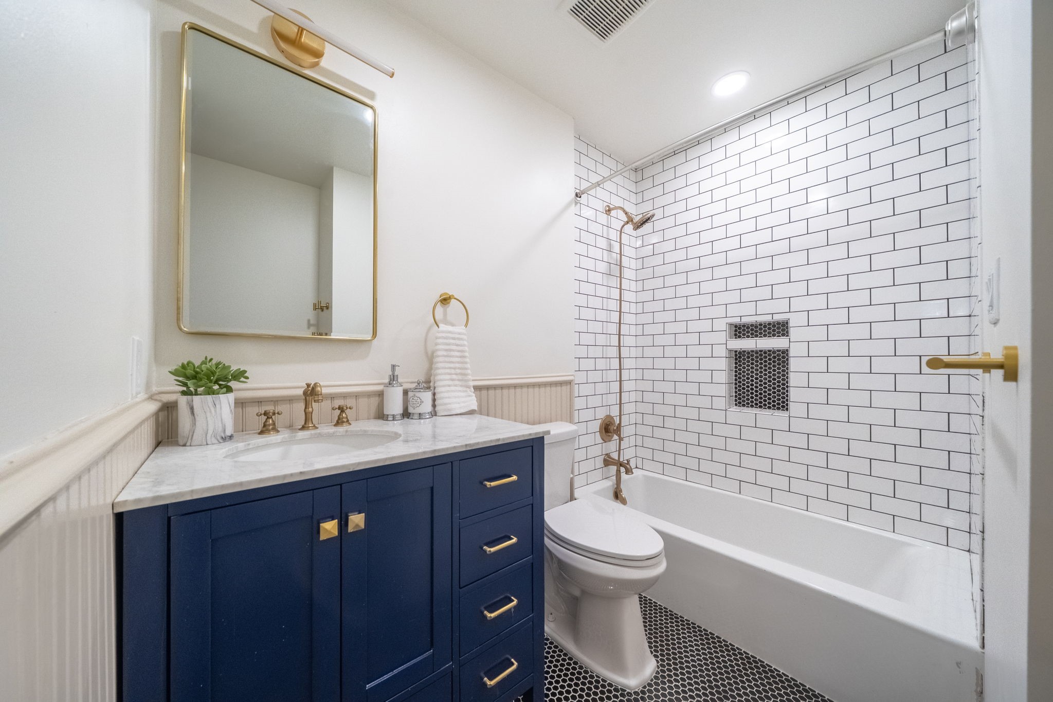 1109 Rutland Street Houston, TX 77008 - Photo 23 of 34 A stunning secondary bathroom featuring timeless black-and-white detailing, elevated with elegant gold accents. Thoughtfully reimagined, this space now offers convenient hallway access, making it as functional as it is stylish.