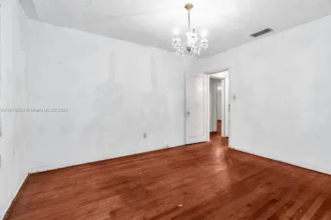 a view of an empty room with wooden floor and chandelier