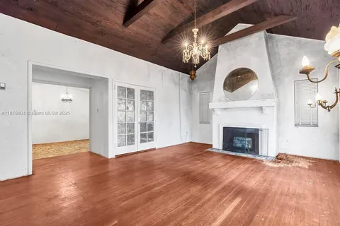 a view of an empty room with wooden floor and a fireplace