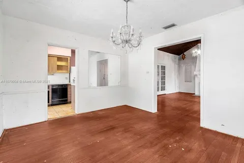 an empty room with chandelier and wooden floor