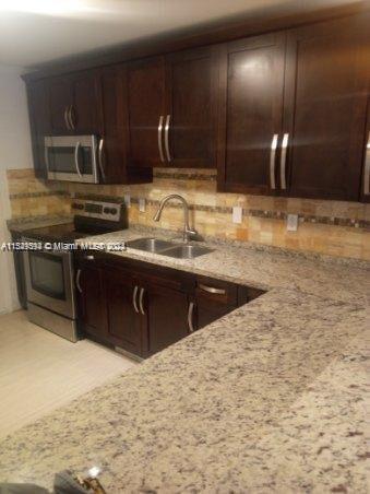 a kitchen with stainless steel appliances granite countertop a sink a stove top oven and granite counter tops