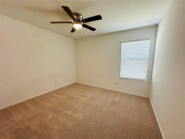 an empty room with a window and a ceiling fan
