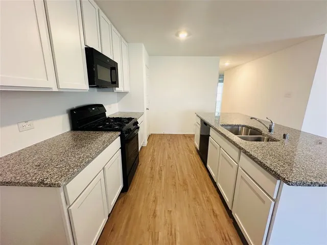 a kitchen with granite countertop sink stove and refrigerator