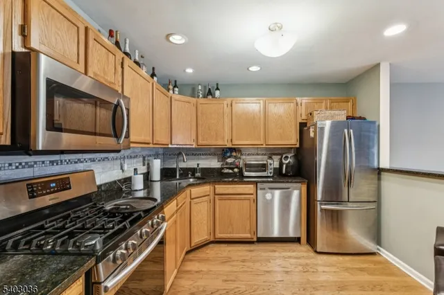 a kitchen with stainless steel appliances granite countertop a stove a refrigerator and a microwave