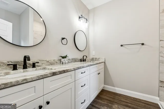 a bathroom with a granite countertop double vanity sink and a mirror