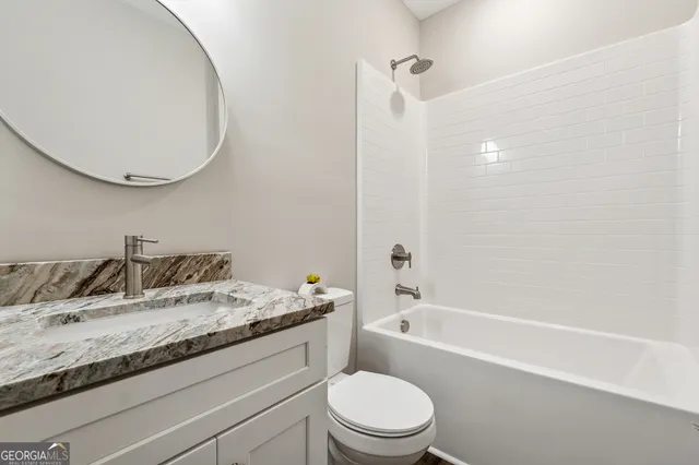 a bathroom with a granite countertop sink a toilet and bathtub