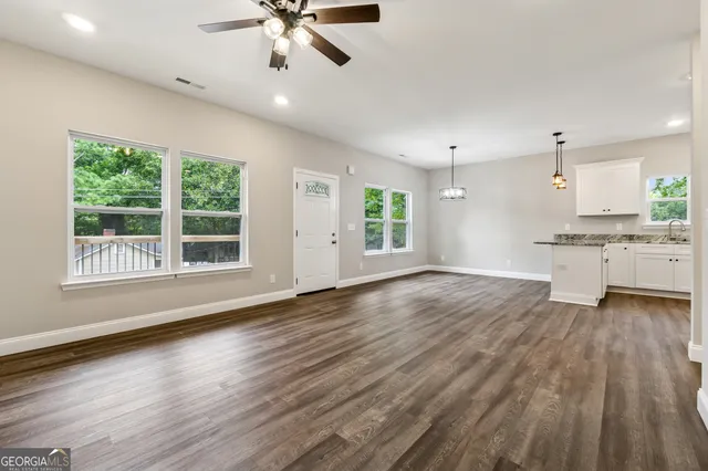 a view of an empty room with a window and wooden floor