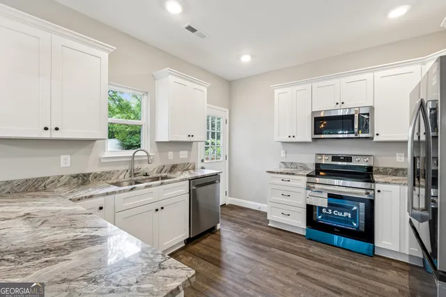 a kitchen with stainless steel appliances granite countertop a stove a sink and a microwave