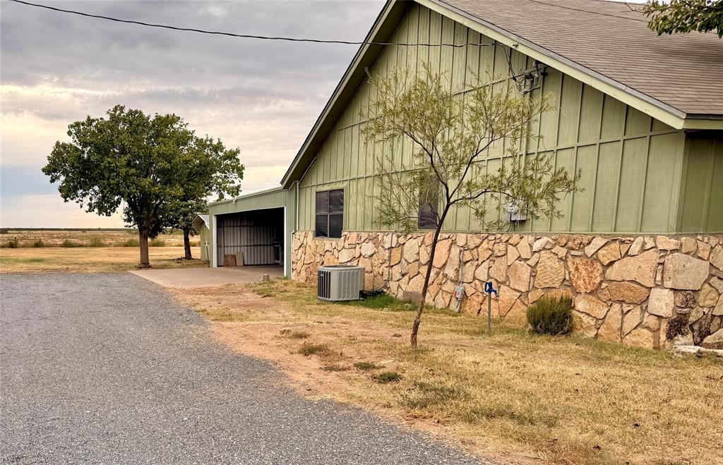 504 Loop Road Quanah, TX 79252 - Photo 3 of 40 View of side of home featuring stone siding, roof with shingles, board and batten siding, garage and driveway