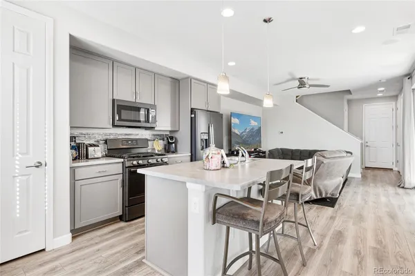 a kitchen with stainless steel appliances kitchen island granite countertop a stove a sink a refrigerator and a microwave