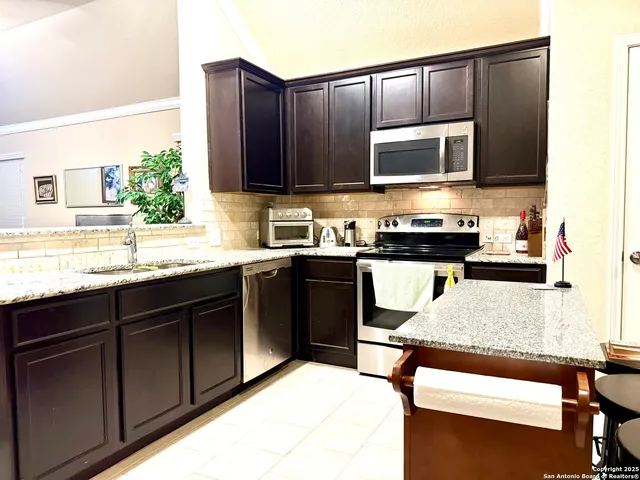 a kitchen with stainless steel appliances granite countertop wooden cabinets a stove top oven a sink and dishwasher