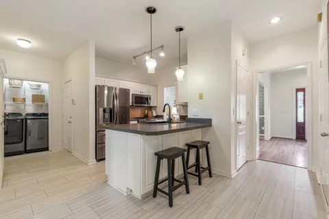a kitchen with kitchen island a counter space a sink appliances and cabinets