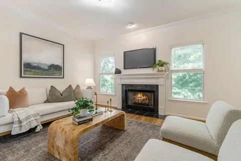 a living room with furniture two windows and a fireplace