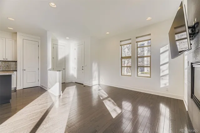 a view of an empty room with window and wooden floor