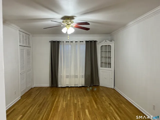 an empty room with wooden floor chandelier fan and closet area