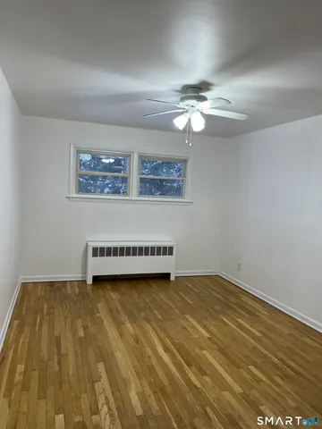 a view of a room with wooden floor and a ceiling fan