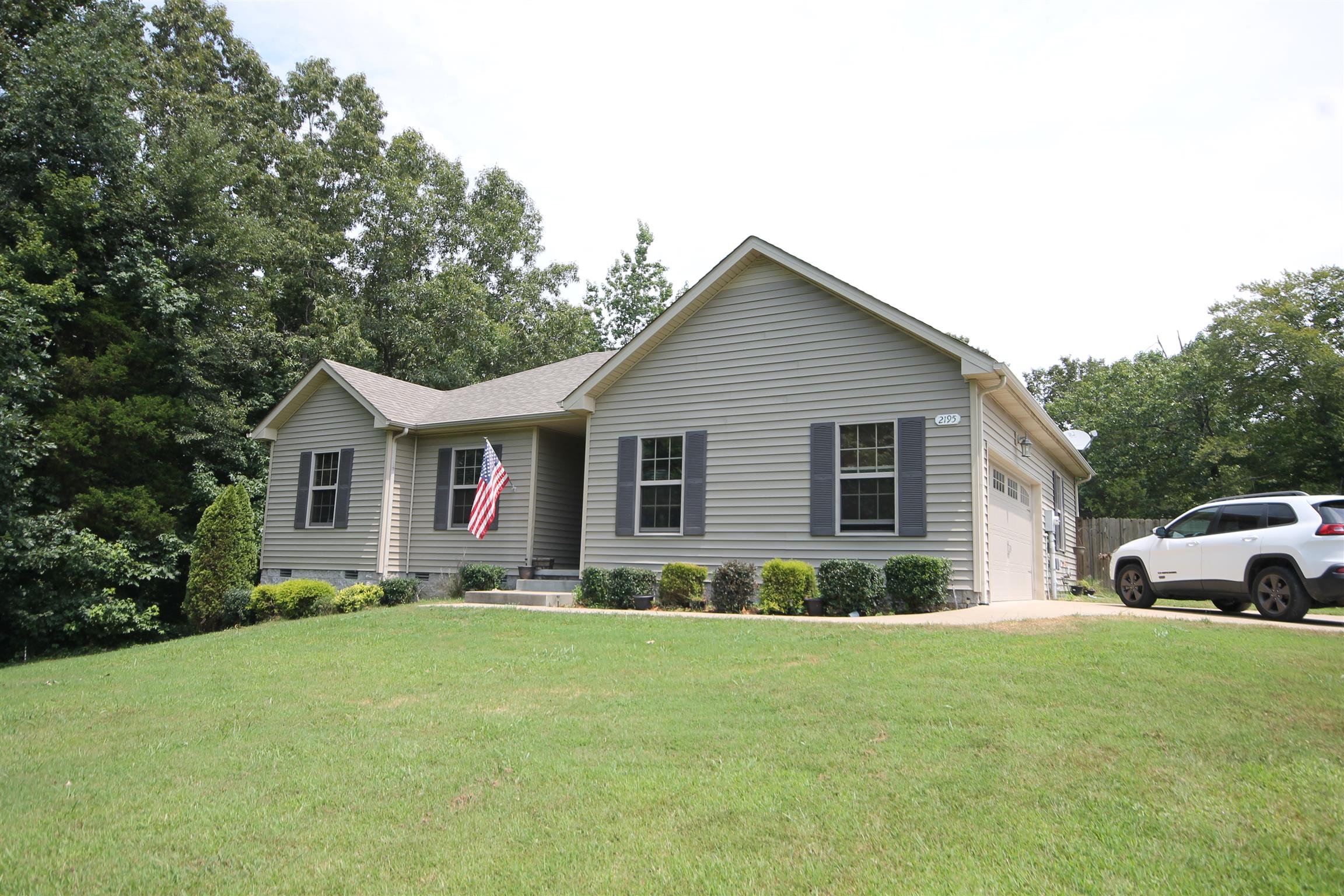 a front view of house with yard and trees in the background