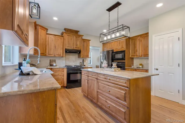a kitchen with stainless steel appliances granite countertop a stove refrigerator and a sink