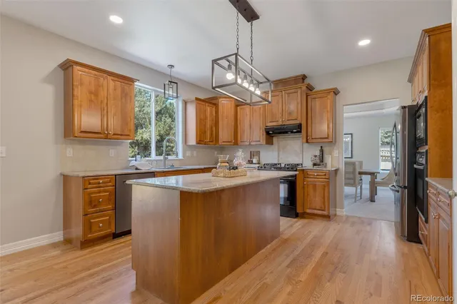 a kitchen with stainless steel appliances granite countertop wooden floors stove top oven and refrigerator