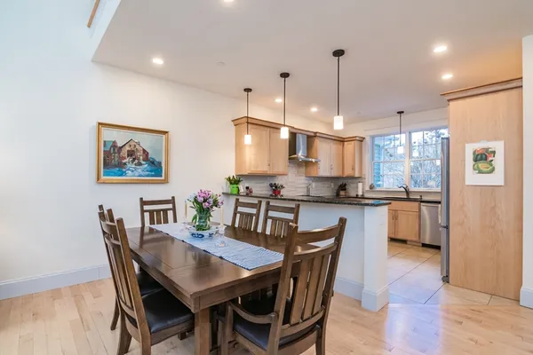 a kitchen with stainless steel appliances granite countertop a dining table chairs and a refrigerator