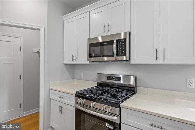 a kitchen with stainless steel appliances granite countertop white cabinets a stove top oven