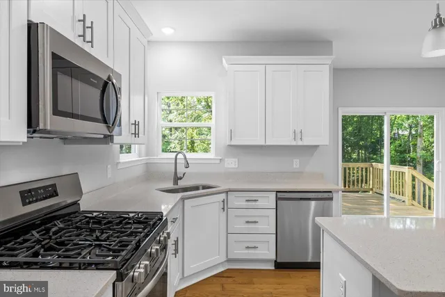 a view of an empty room with a window and kitchen view