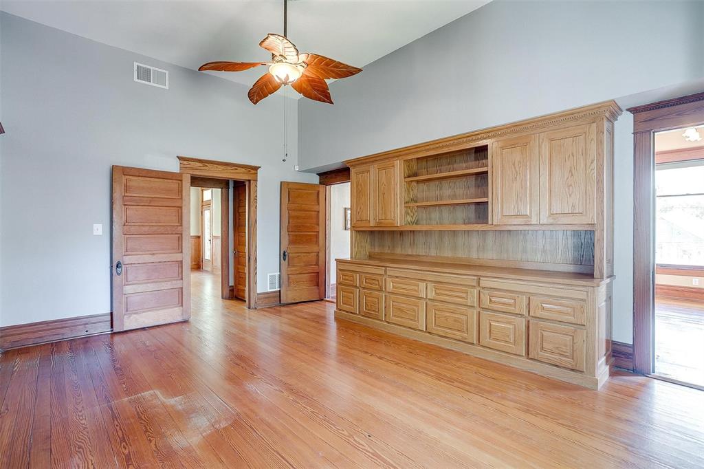 708 South Waco Street Weatherford, TX 76086 - Photo 28 of 35 a kitchen with wooden floors and white cabinets