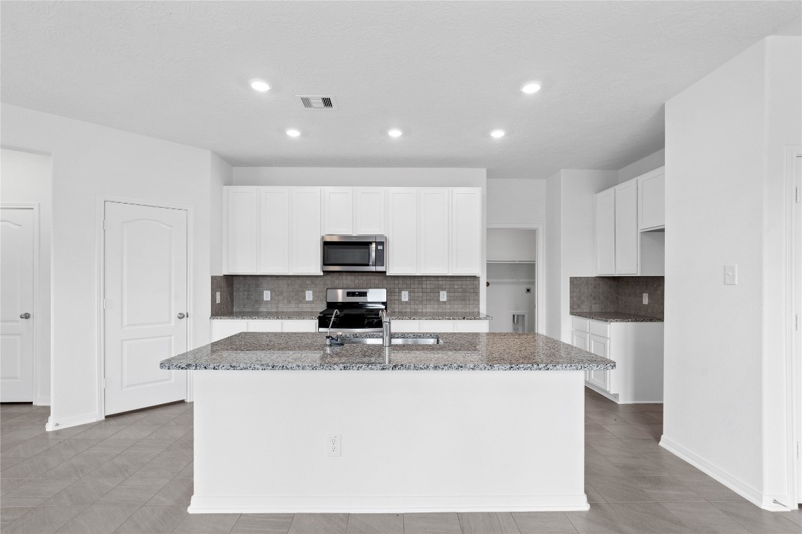 833 Mustang Rdg Terrace Magnolia, TX 77354 - Photo 10 of 21 a kitchen with kitchen island stainless steel appliances a sink a stove a microwave a sink and cabinets