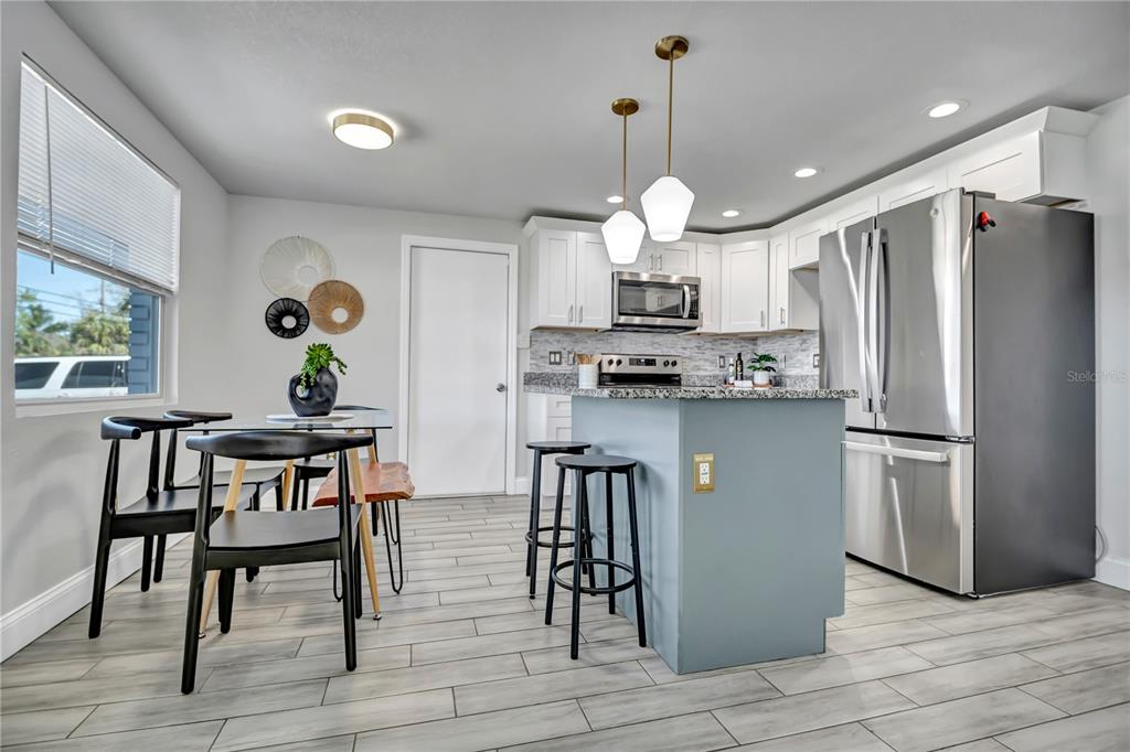 6510 West Chelsea Street Tampa, FL 33634 - Photo 6 of 20 a kitchen with stainless steel appliances granite countertop a refrigerator a sink dishwasher a stove and a dining table with wooden floor