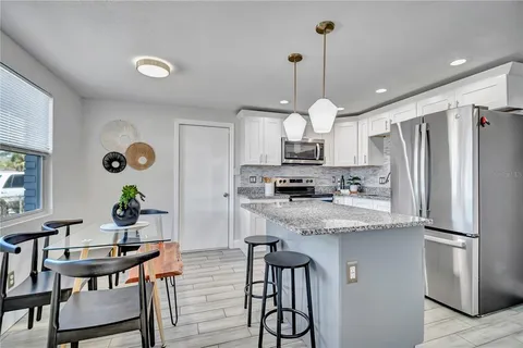 a kitchen with stainless steel appliances granite countertop a refrigerator a stove a sink dishwasher and white cabinets with wooden floor