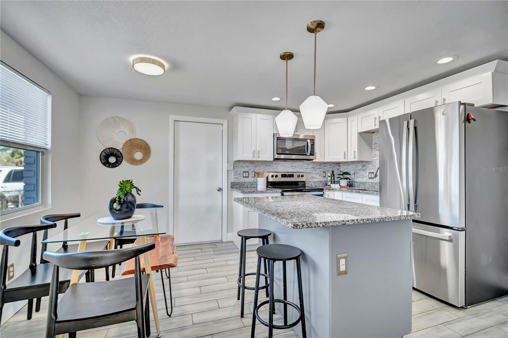 6510 West Chelsea Street Tampa, FL 33634 - Photo 7 of 20 a kitchen with stainless steel appliances granite countertop a refrigerator a stove a sink dishwasher and white cabinets with wooden floor