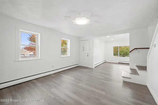 a view of a big room with wooden floor and windows