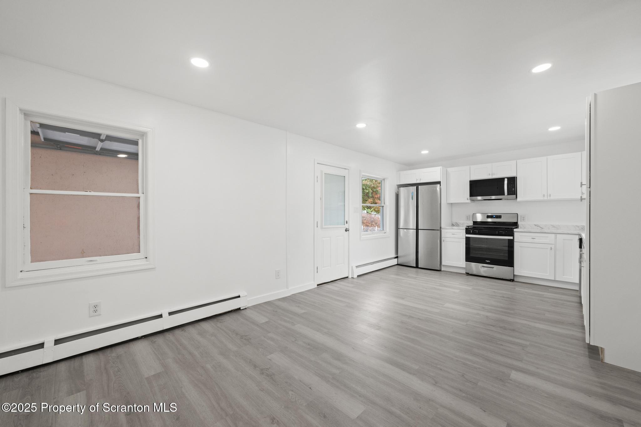 527 St Frances Cabrini Avenue, Unit 2 Scranton, PA 18504 - Photo 4 of 36 an empty room with wooden floor kitchen view and a window