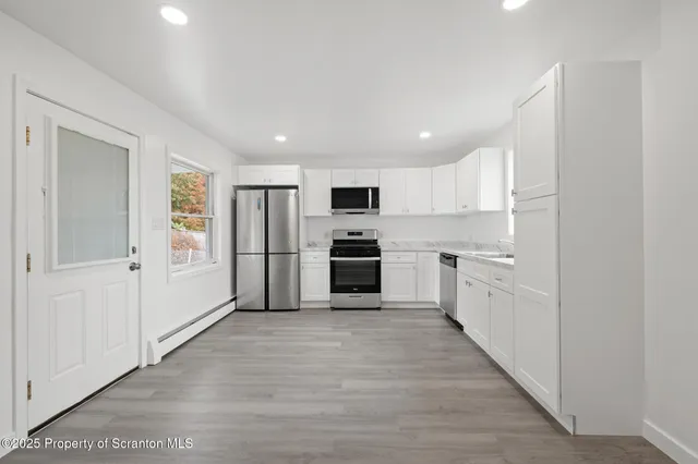 a kitchen with white cabinets and stainless steel appliances
