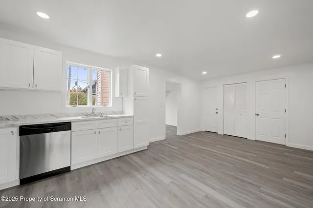 a kitchen with granite countertop white cabinets and wooden floor