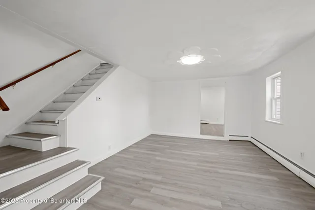 a view of an empty room with stairs and a ceiling fan